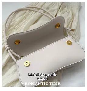 Gros plan du sac en cuir beige avec doubles anses et fermoir magnétique doré