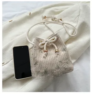 Detail of woven bucket bag featuring floral embroidery and drawstring with metal ball
