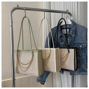 Detailed view of woven tote bags with gold chain accents and slim shoulder straps