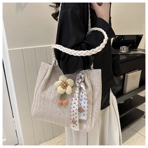 Détail du sac cabas tissé avec bandoulière tressée, breloque fleur et foulard décoratif