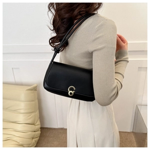 Detail of minimalist black leather underarm bag with gold metal buckle and knotted strap