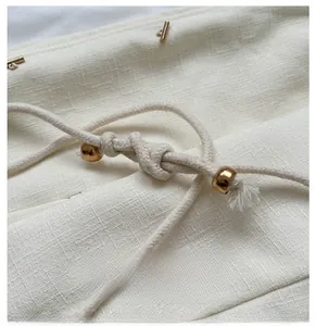 Detailed view of woven straw bucket bag with cotton drawstring and golden metal bead accents