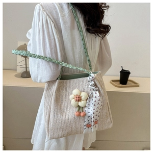 Détail du sac cabas tissé crème avec poignées vertes et breloque florale décorative