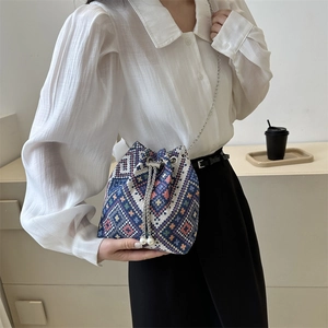 Ethnic woven drawstring bucket bag with geometric patterns, pearl charms and chain strap