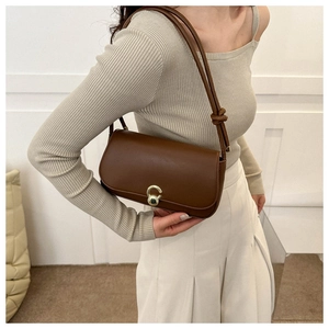 Brown vintage rectangular shoulder bag with golden round buckle worn with beige knitwear