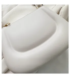 Close-up of cream leather saddle bag with matte gold metal buckle and stitching details