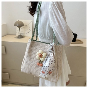 Détail du sac cabas en paille avec bandoulières vertes et foulard floral décoratif