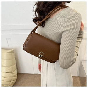 Detail of dark brown leather underarm bag with unique gold clasp and knotted strap detail