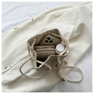 Interior view showing capacity of woven bucket bag with phone and wallet inside