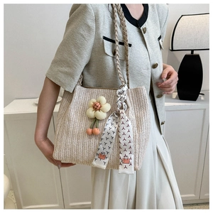 Détail du cabas tissé beige avec breloque florale et poignée en foulard de soie à motif