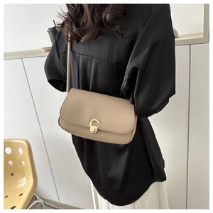 Beige rectangular underarm bag with gold ring buckle worn by model in black shirt