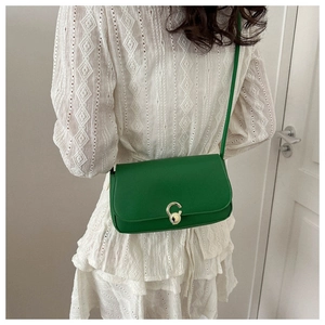 Detail of green PU leather shoulder bag with circular gold metal buckle and thin strap
