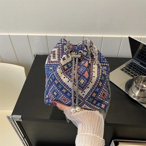 Ethnic woven bucket bag with blue geometric patterns, chain strap and pearl drawstring details