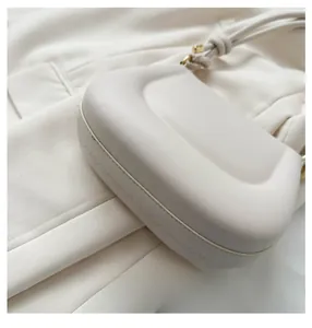 Detailed close-up of the wide base and stitching on an off-white leather saddle bag