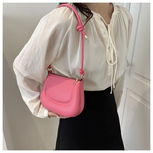 Hot pink saddle bag with knot strap detail and gold hardware shown on model