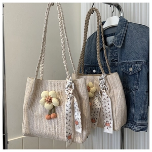 Détail d'un sac cabas en paille tressée avec fleurs décoratives et foulard en soie imprimé