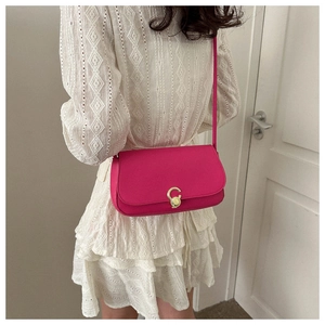 Detail of hot pink leather crossbody bag featuring a minimalist golden C-shaped rotating clasp