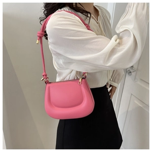Model wearing a rose pink faux leather saddle bag as a chic shoulder underarm purse