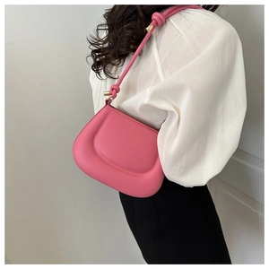 Close-up of bright pink saddle bag with knot strap detail and golden metal hardware