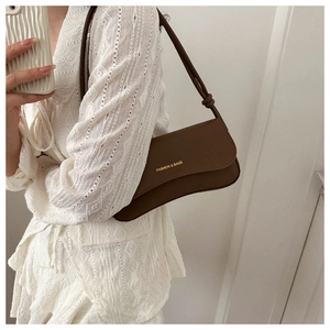 Détail du sac bandoulière en cuir caramel avec logo doré et bandoulière nouée chic