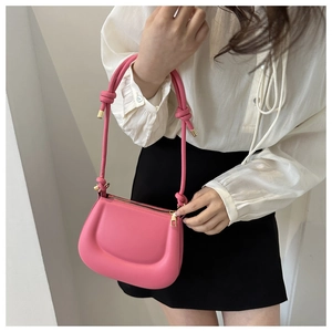 Detail of vibrant pink saddle bag with thick knotted strap and gold hardware accents