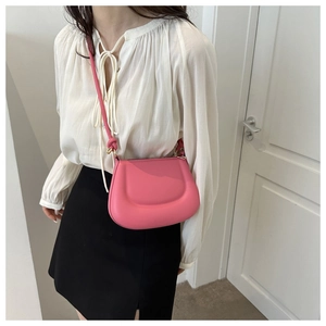 Detail of fuchsia leather saddle bag with stylish knotted shoulder strap and gold hardware