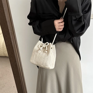 Handmade cream woven straw bucket bag with drawstring closure for summer crossbody wear