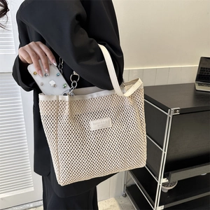 Borsa tote in paglia con finiture in pelle bianca tenuta da una modella in un ufficio