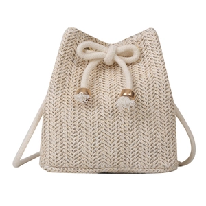 Handwoven beige straw bucket bag with elegant tassel drawstring and rustic summer style