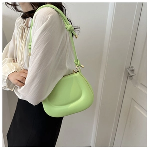 Detail of neon green shoulder bag with stylish knotted strap and golden metal accents
