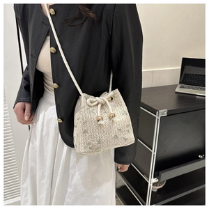 Close-up of beige woven bucket bag featuring green floral embroidery and drawstring closure