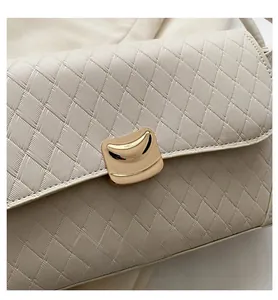 Detail of beige woven texture handbag featuring a modern gold U-shaped metal buckle clasp