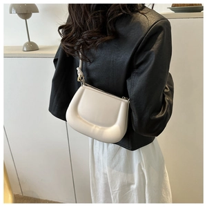 Close-up of cream half-moon bag featuring unique knotted shoulder strap details