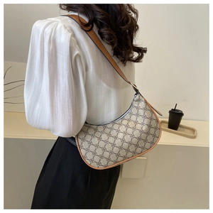 Detail of vintage beige hobo bag with brown leather trim and clover pattern on the strap