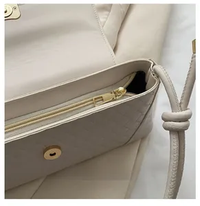 Macro view of woven beige baguette bag featuring smooth zipper and knotted rope strap