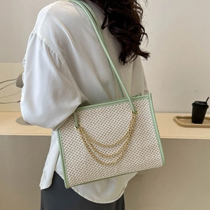 Large straw tote bag in light green with metallic chain accents and leather trim