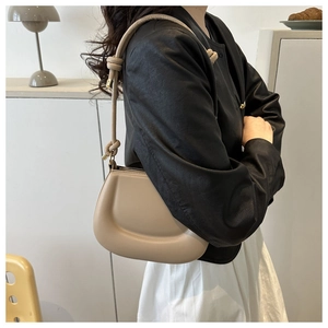 Close-up of beige cloud shoulder bag featuring knotted strap and 3D textured silhouette