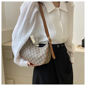 Detailed view of beige clover pattern crescent bag with brown leather shoulder strap