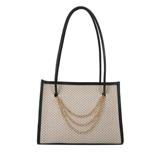 Large capacity straw tote bag with black leather trim and decorative gold chains