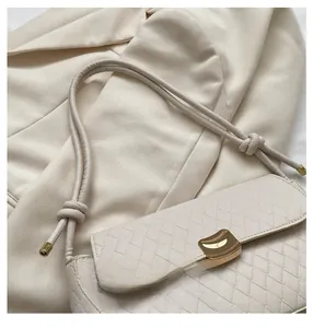 Close-up of beige woven texture handbag with golden buckle and knotted leather strap details