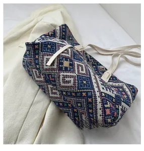 Detail view of ethnic canvas tote bag with colorful patterns on a white blazer
