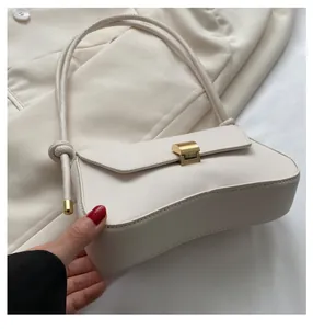 Detail showing creamy white baguette bag buckle and knot shoulder strap on blazer background