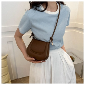 Detail of dark brown leather saddle bag with shoulder strap knot and metal ends