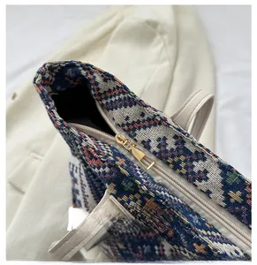 Detail of a smooth golden metal zipper and colorful woven pattern on a canvas tote bag