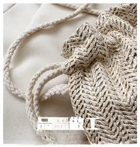 Close-up of woven straw bucket bag showing fine texture and braided drawstring detail