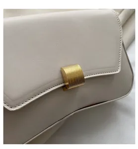 Close-up of beige leather bag featuring a gold ribbed metal clasp and stitching detail