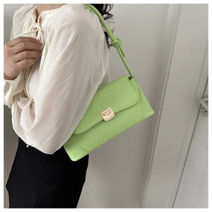 Close-up of lime green quilted baguette bag with gold wavy buckle and knotted strap