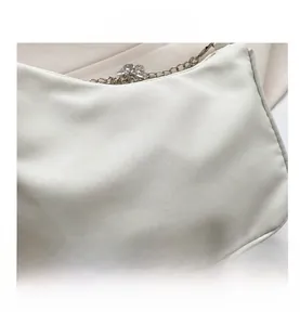 Close-up of white silk handbag featuring silver chain strap and sparkling butterfly charm