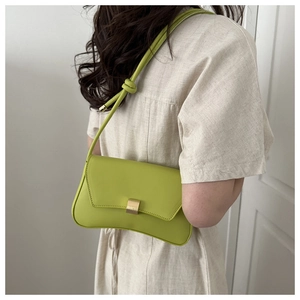 Lime green baguette shoulder bag with gold clasp and knotted strap on model in white dress