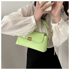 Detail of neon green baguette bag featuring quilted leather and gold metal lock closure